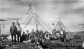 People in front of two teepees with unknown lake in background